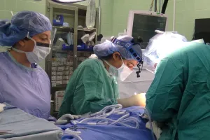 Trois prestataires de soins de santé en blouse effectuent une chirurgie