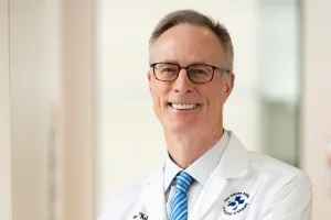 A man in glasses looks at the camera