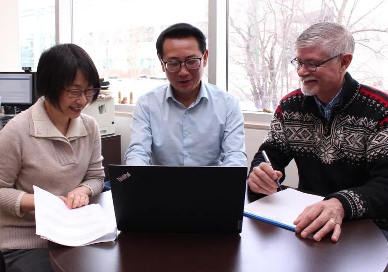 Three people look at a computer screen