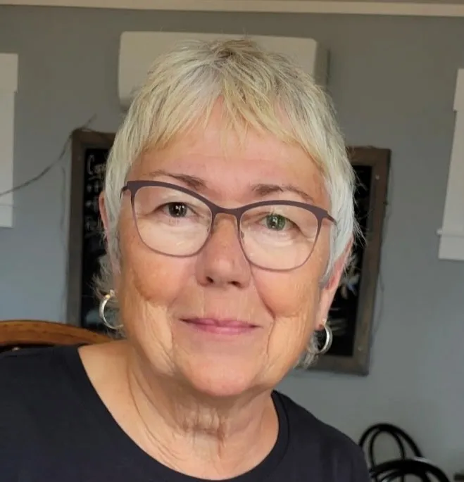 An older woman with short white hair smiles at the camera
