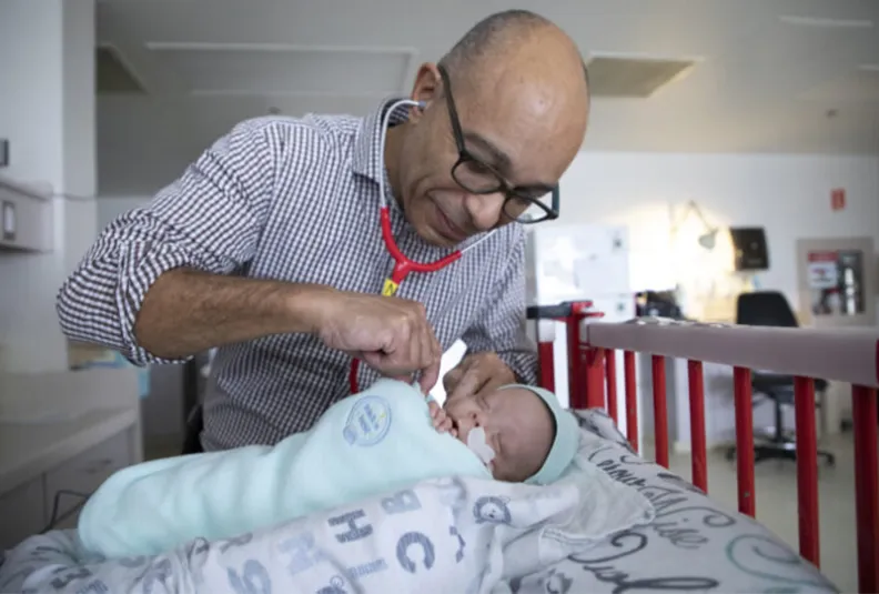 Dr. Bernard Thébaud listens to the lungs of a premature baby.