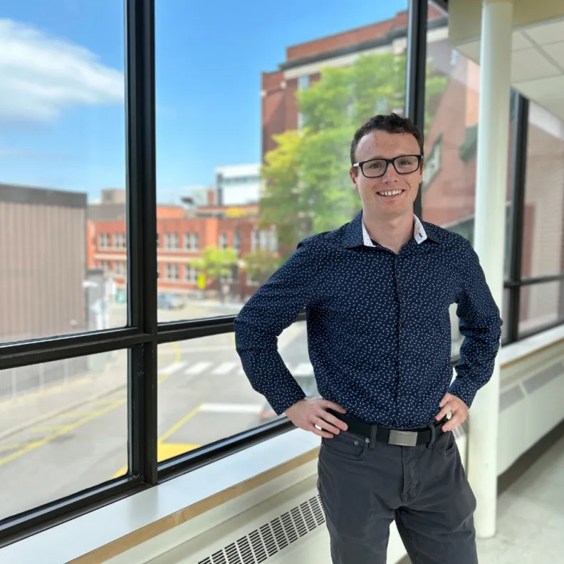 A smiling man stands in the hallway of a hospital 