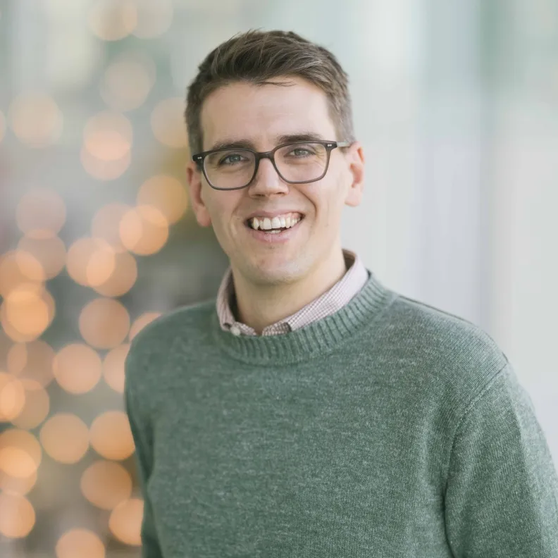 A man wearing glasses smiles at the camera