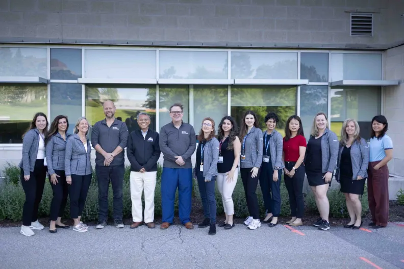 A group of people smiling in front of a building