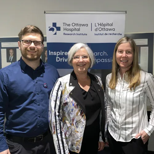 Three people stand together and smile