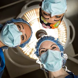 Three surgeons wearing surgical masks and caps 
