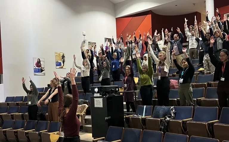 A group of people in an auditorium raising their hands