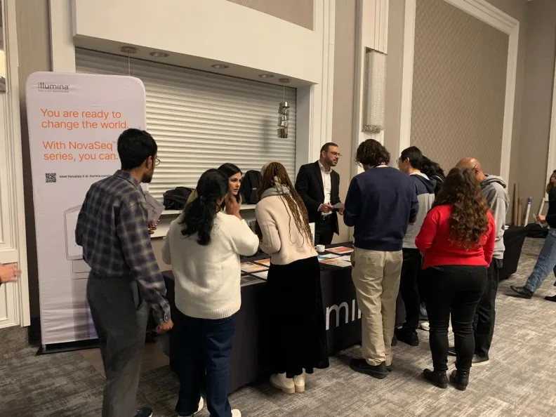 People crowd around a table at a conference event