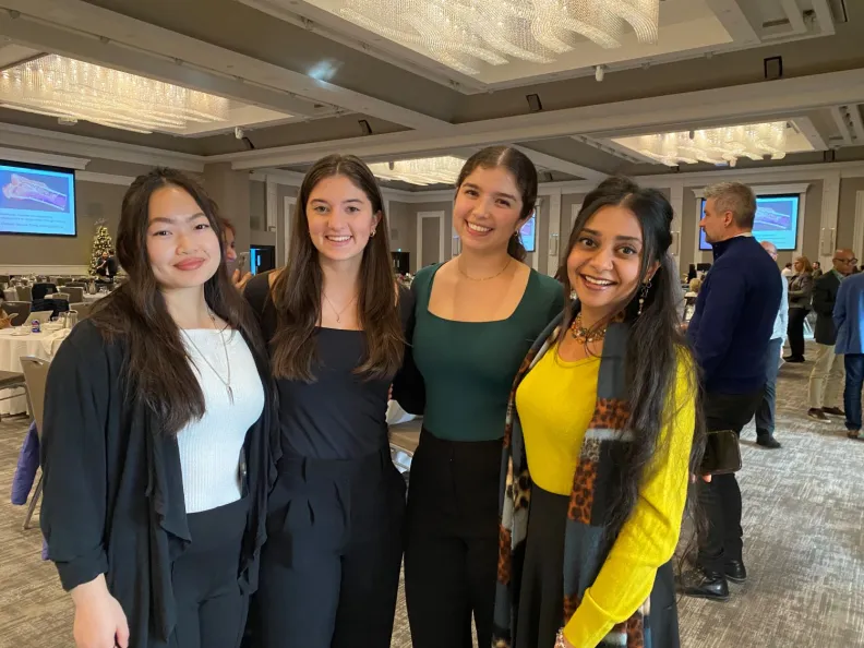 Four people smiling while attending a conference