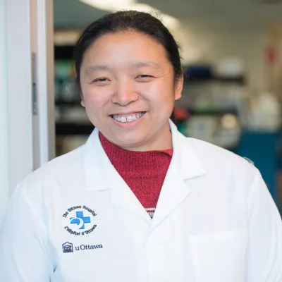 A woman wearing a lab coat smiles at the camera