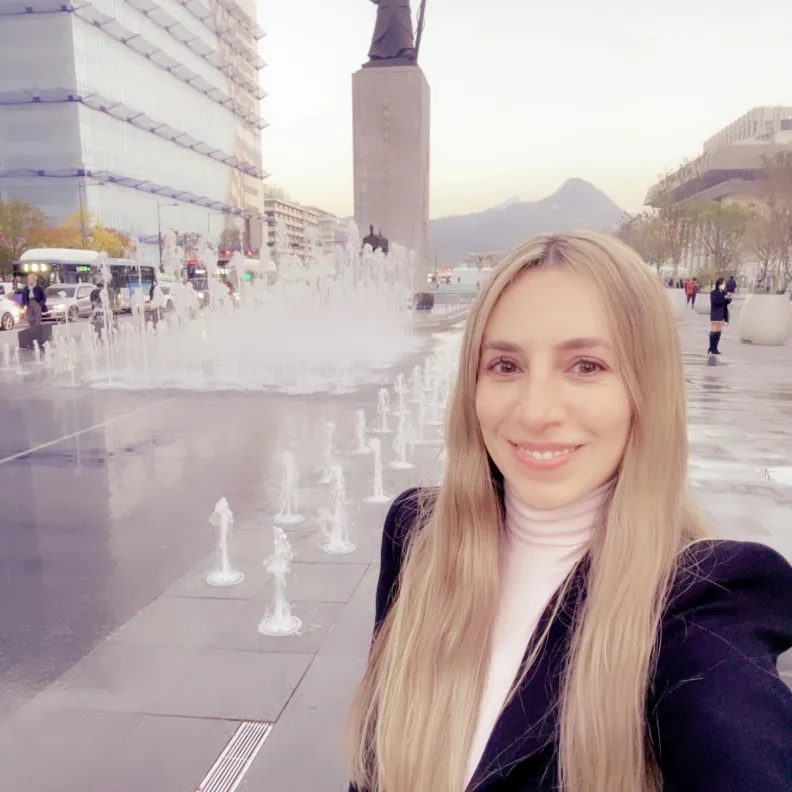 A woman stands in front of a water fountain