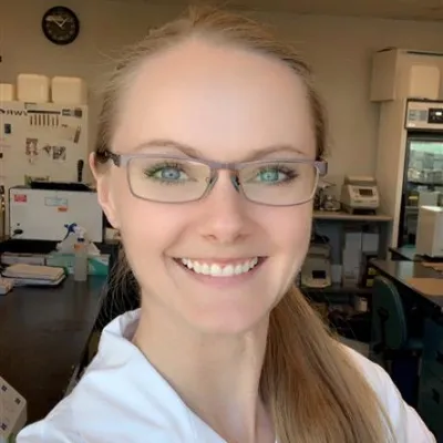 A woman with glasses smiles at the camera