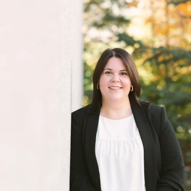 A woman standing outside smiles at the camera
