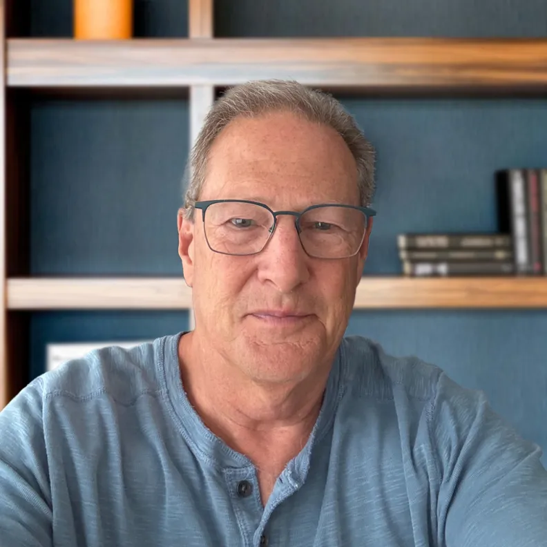 A man sits in front of a bookshelf