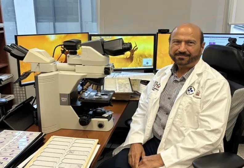 A man sits in front of a microscope